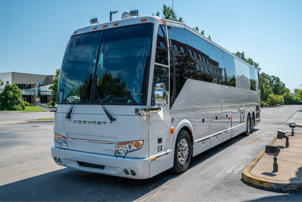 Front side view of a Prevost H345 bus conversion for sale, highlighting its sleek, aerodynamic design, perfect for an entertainer bus on the road.
