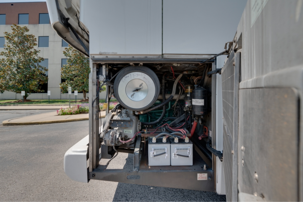 View of the rear compartment of a Prevost H345 bus conversion for sale, showing power systems and storage, ideal for entertainer buses needing reliable travel equipment.