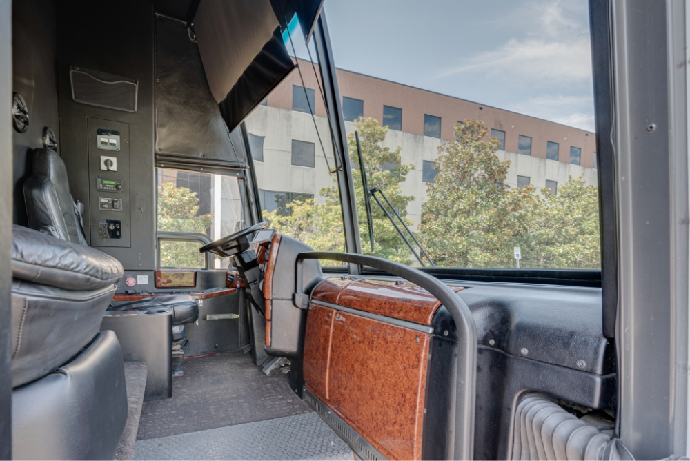 View of the driver's seat and dashboard in a Prevost H345 bus conversion, showcasing the well-maintained driver area for comfortable and efficient operation.