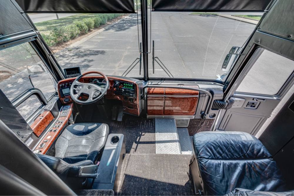View of the driver's cockpit and dashboard in a Prevost H345 bus, showcasing the well-organized controls and spacious driving area.
