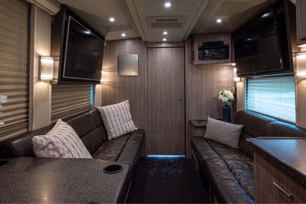 Interior lounge area of a Prevost H345 bus, featuring comfortable seating, flat-screen TV, and a modern design for relaxation and entertainment.