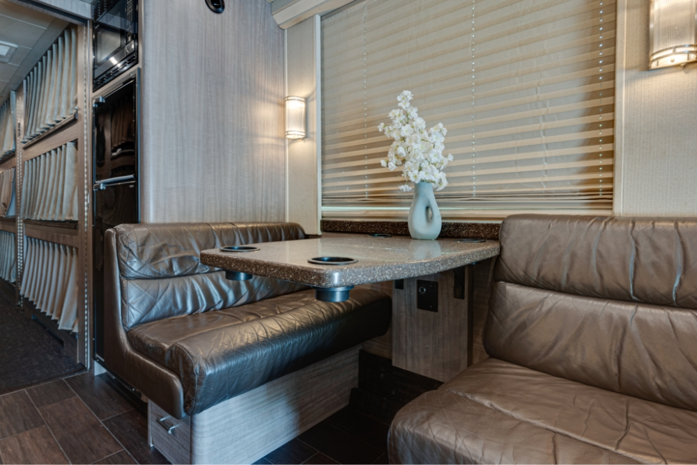 Booth-style seating area in a Prevost H345 bus conversion, ideal for dining or work, offering comfort and practicality for long trips.