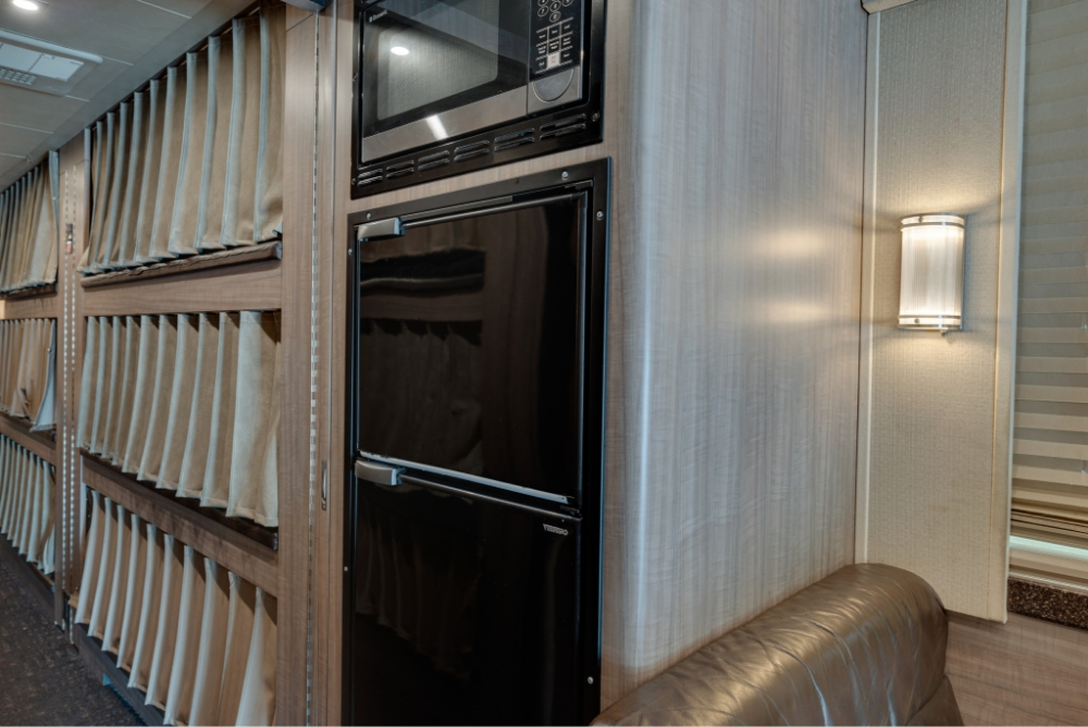 View of the built-in fridge and storage compartments inside a Prevost H345 bus, designed for convenience and efficient use of space.