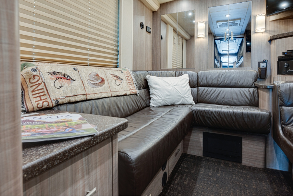 Close-up view of a large sectional leather couch with pillows, providing a cozy and stylish seating option inside the Prevost H345 bus.
