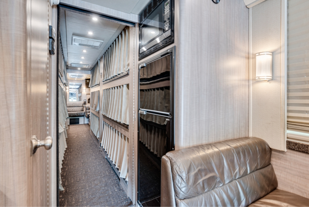 Hallway view in a Prevost H345 bus, featuring multiple bunk beds and a seating area, designed for comfortable sleeping accommodations on long trips.