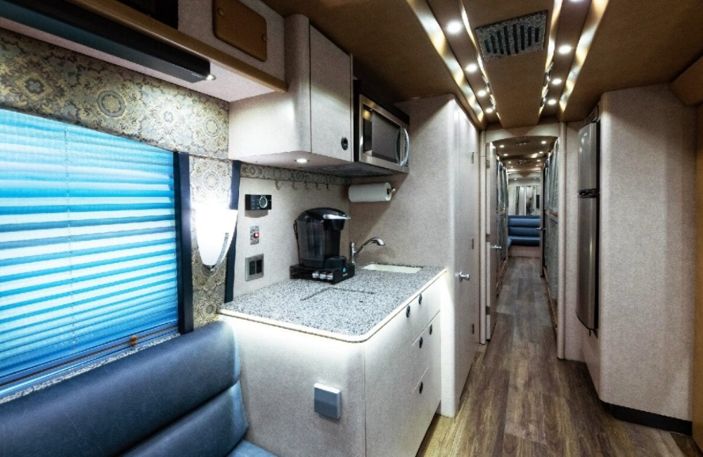 Interior hallway view of the 2007 Prevost XLII, featuring modern cabinetry and seating along the kitchen area with bright lighting