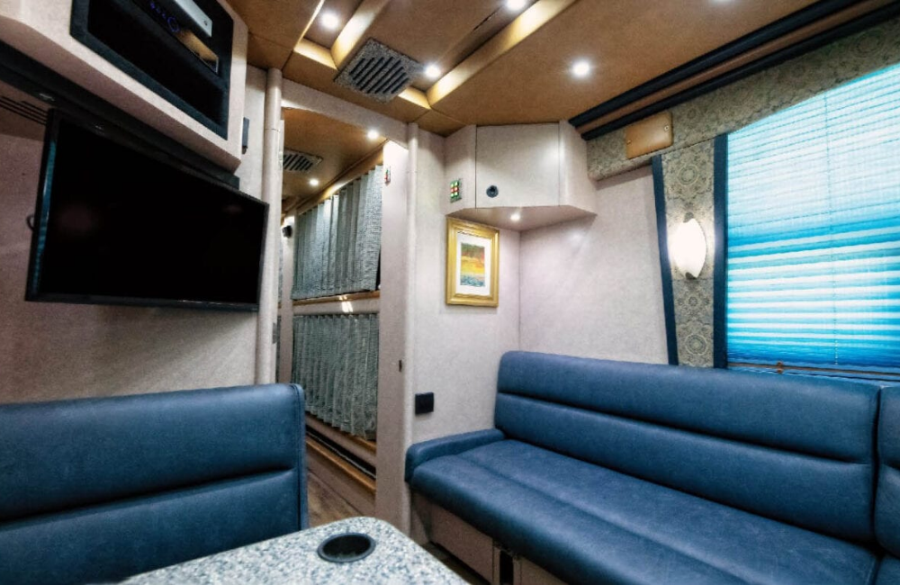 Close-up of the dining area with modern seating and a mounted TV inside the 2007 Prevost XLII bus conversion