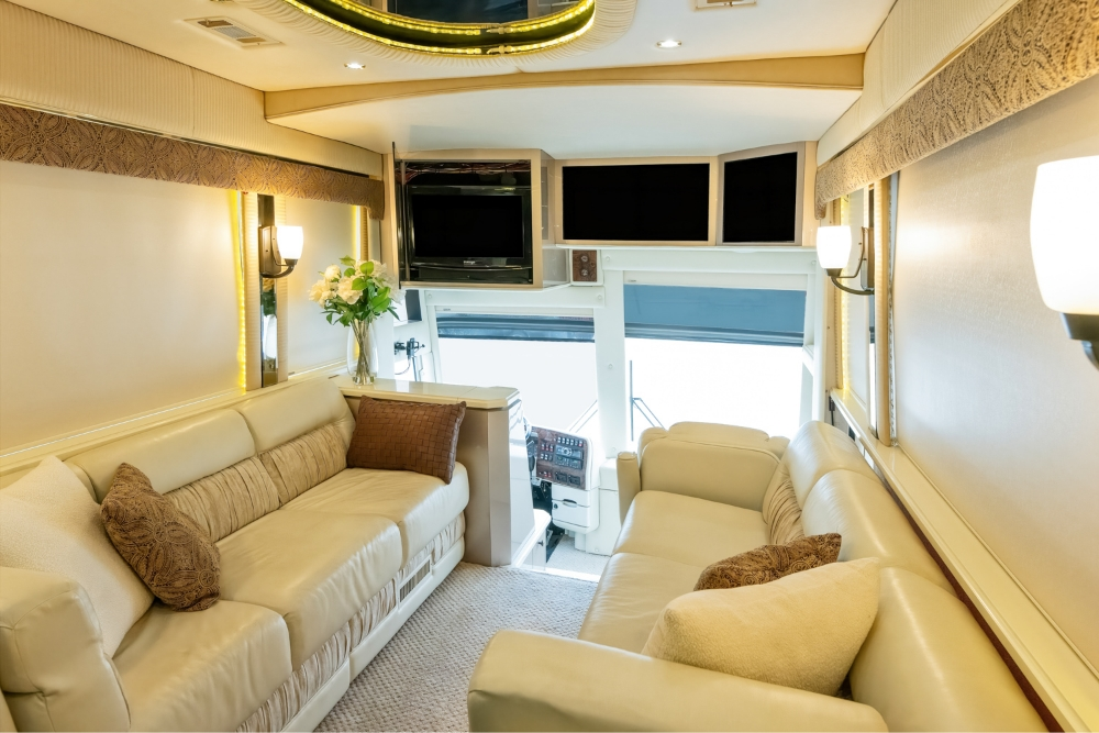 Front living area of a 2000 Prevost H345 bus conversion, featuring comfortable sofas and a TV, creating a cozy space for relaxation or entertainment on the road.