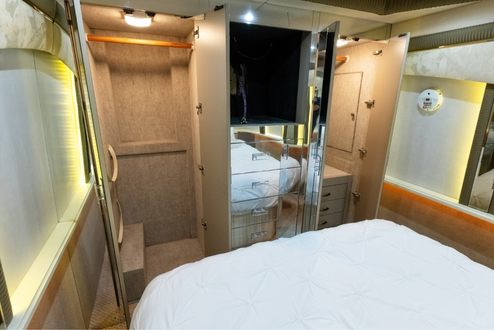 Master bedroom inside a 2000 Prevost H345 bus conversion, featuring a spacious bed and soft ambient lighting, ideal for luxury motorhome living.