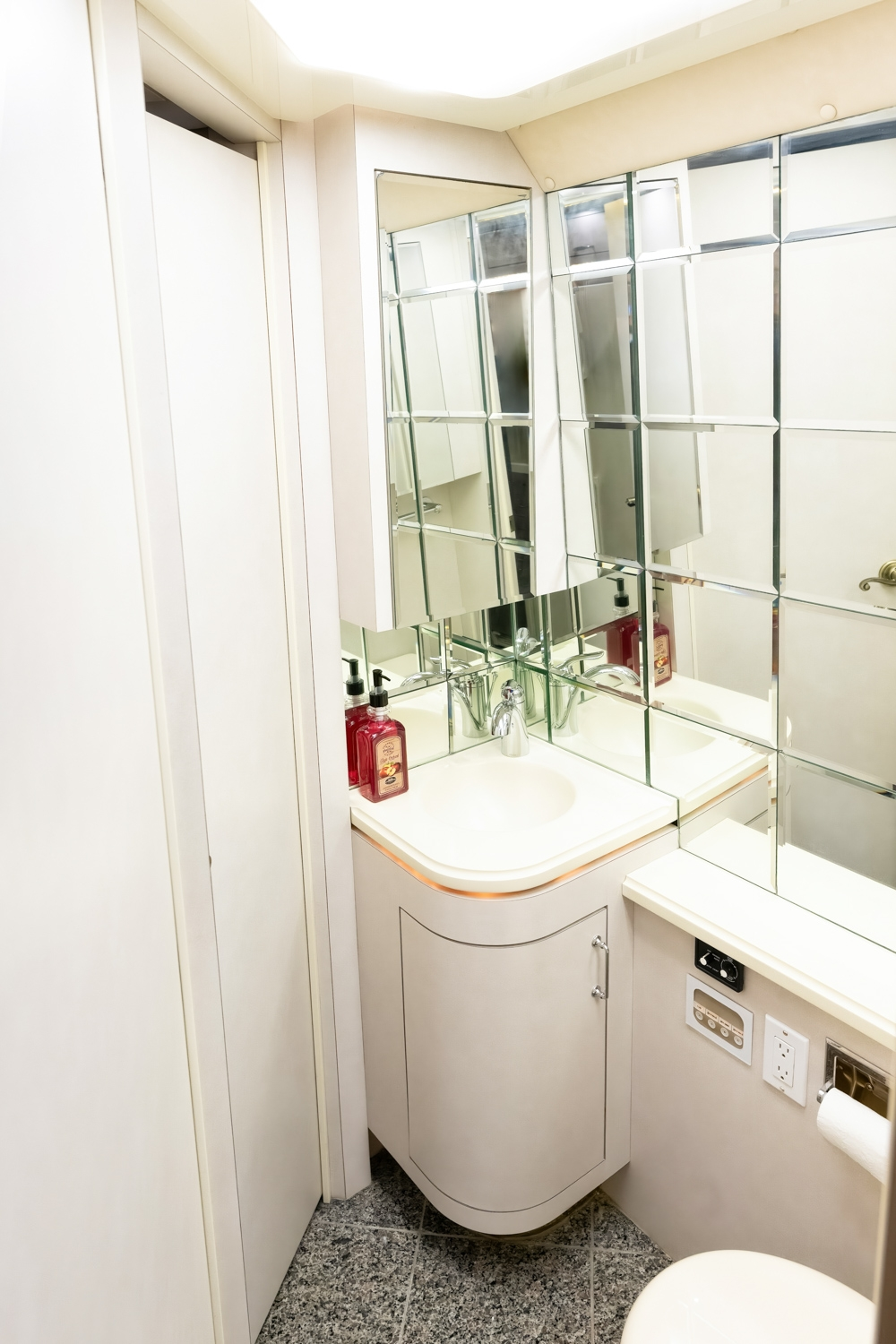 Modern bathroom vanity with a sink and mirrored backsplash inside a 2000 Prevost H345 motorhome, offering sleek design and practicality.