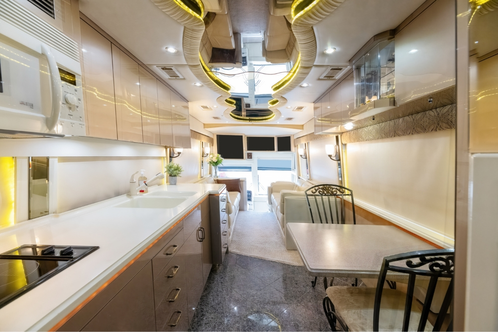 Modern kitchen inside a 2000 Prevost H345 motorhome for sale, showcasing sleek countertops, dining space, and high-end appliances for a comfortable living experience.