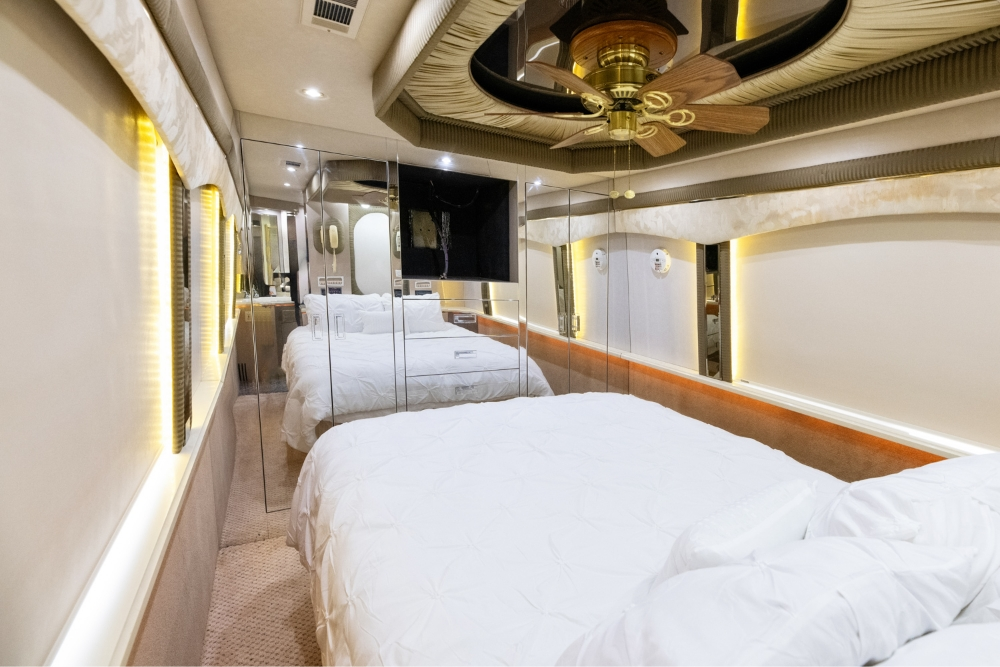 Luxurious bedroom in a 2000 Prevost H345 motorhome for sale, showcasing a comfortable bed and stylish hallway leading to the living areas.