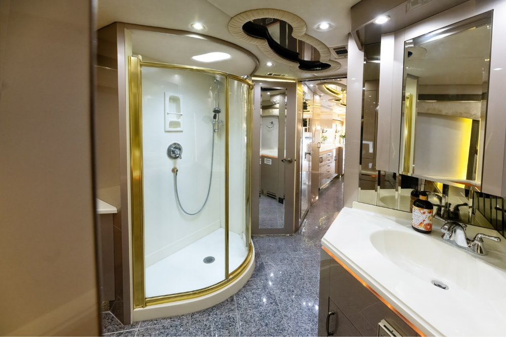 Luxurious bathroom inside a 2000 Prevost H345 bus conversion, featuring a large shower, vanity, and modern fixtures, ideal for a motorhome setup.