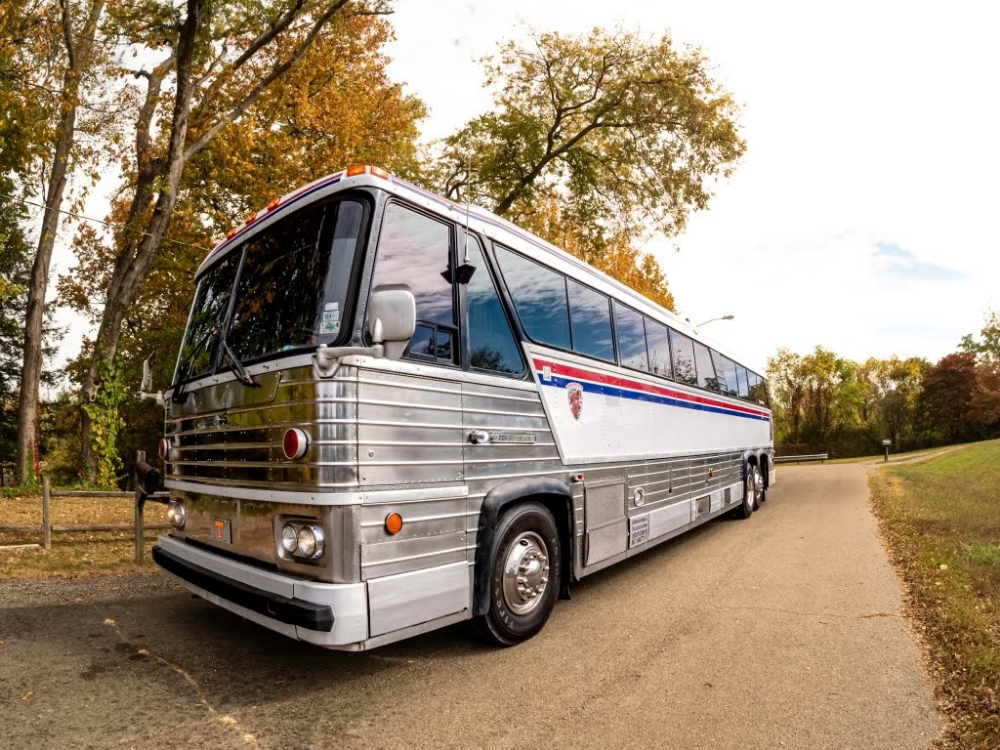 Angled side view of a 1976 MCI 8 bus conversion for sale, with its retro exterior and spacious layout, designed for executive travel and comfort.