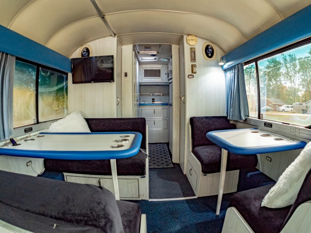 Rear lounge dining area in a 1976 MCI 8 Custom Coach, featuring a table and booth seating, ideal for executive dining or meetings during travel.