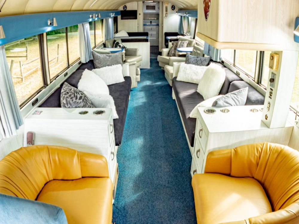 Long view of the living area in a 1976 MCI 8 Custom Coach Conversion, showcasing multiple seating options and a bright, open layout designed for comfort.