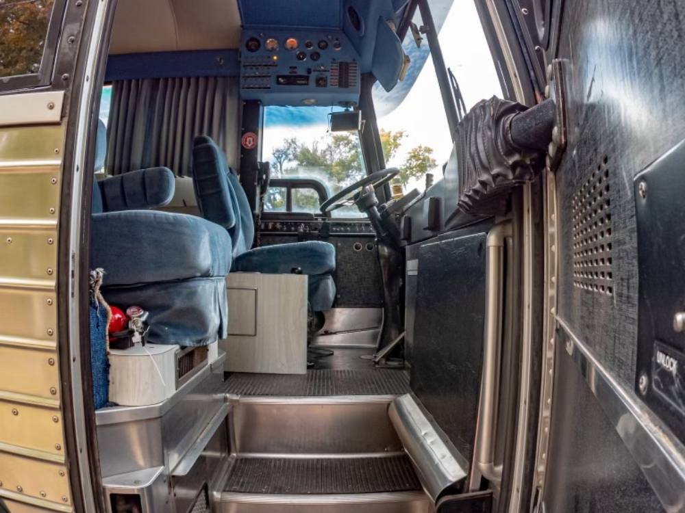 Entry area and steps leading into the interior of a 1976 MCI 8 Custom Coach, showcasing easy access to the driver's seat and bus lounge area.