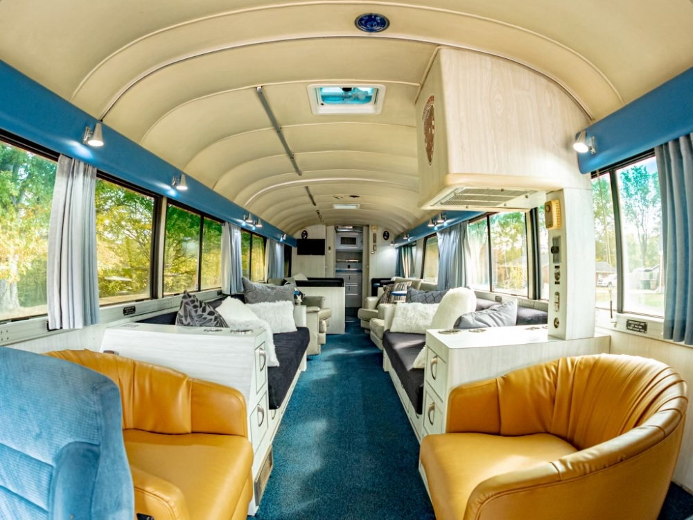 Wide view of the open lounge area in a 1976 MCI 8 Custom Coach, showcasing comfortable seating and large windows, ideal for luxury executive travel.