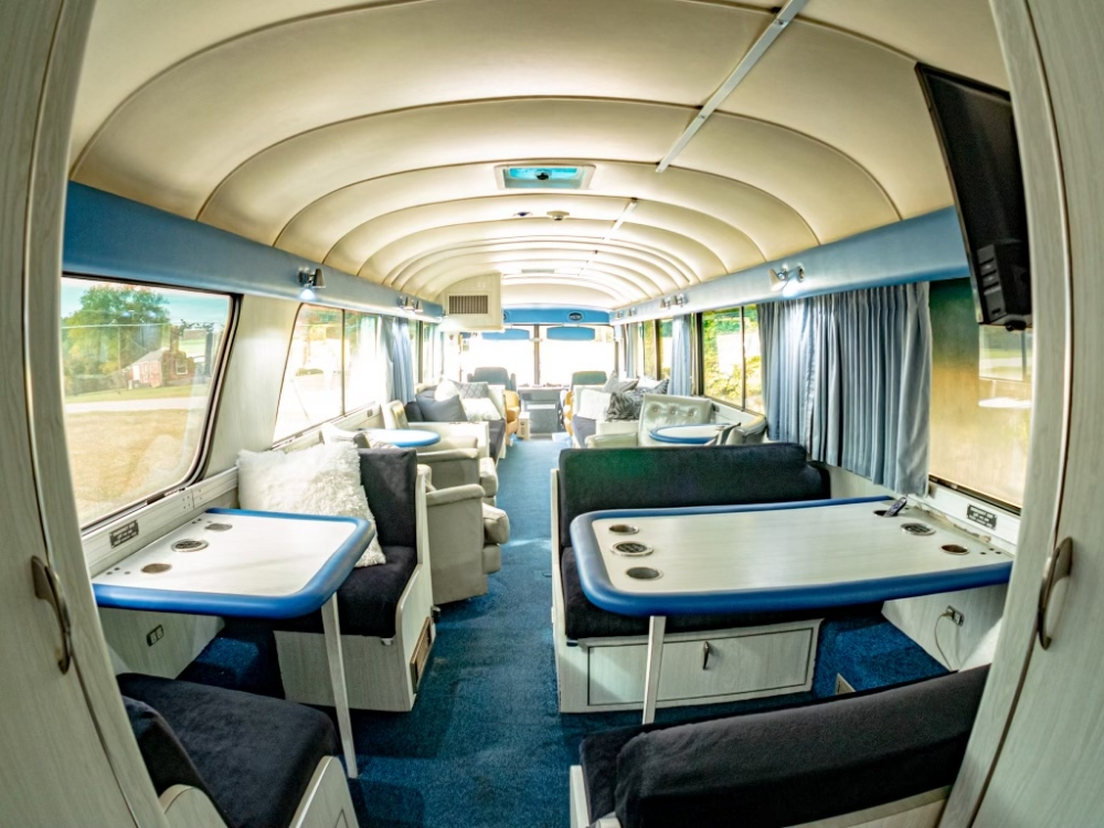 Rear view of the lounge and dining space in a 1976 MCI 8 bus conversion for sale, offering a functional and stylish setup for executive or personal use on the road.