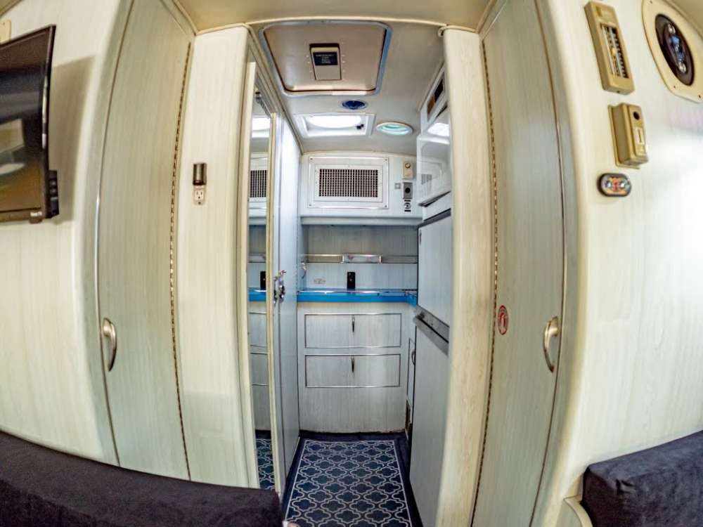 Interior view of a 1976 MCI 8 Custom Coach Conversion, showing the narrow hallway leading to the kitchen and living space, ideal for an executive coach setup.