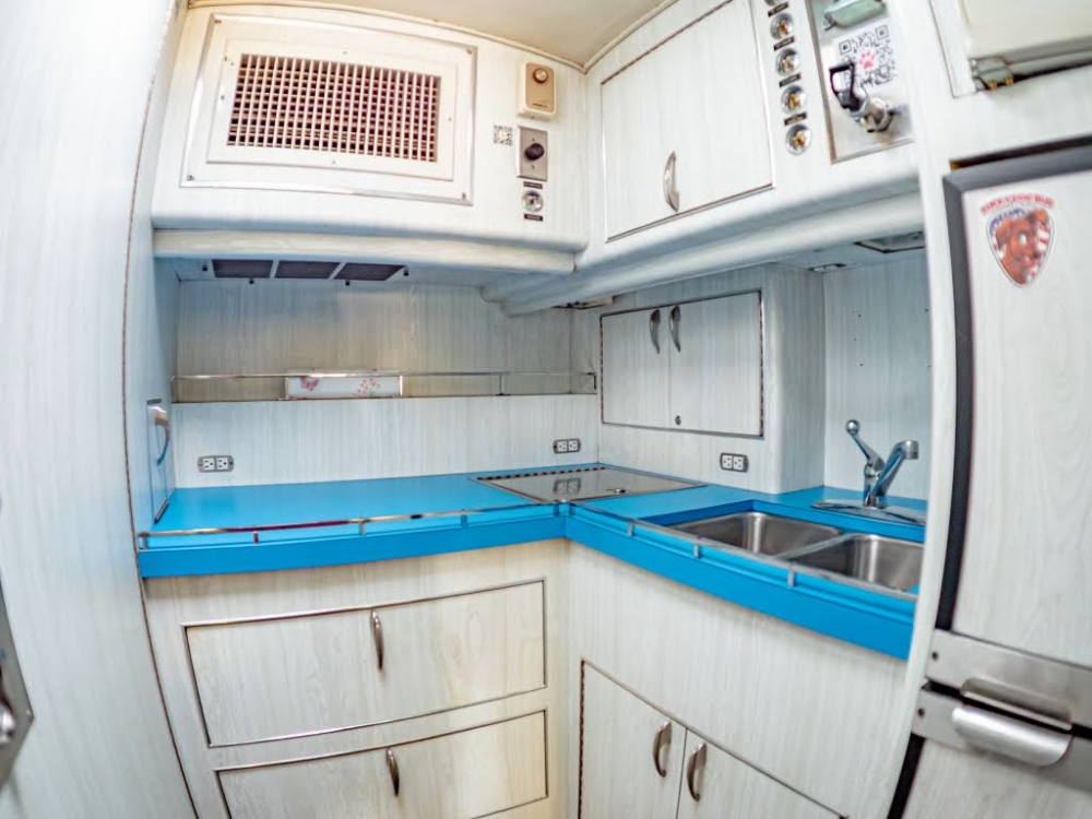 Fully equipped kitchen inside a 1976 MCI 8 Custom Coach Conversion, featuring blue countertops and modern appliances, perfect for executive travel.