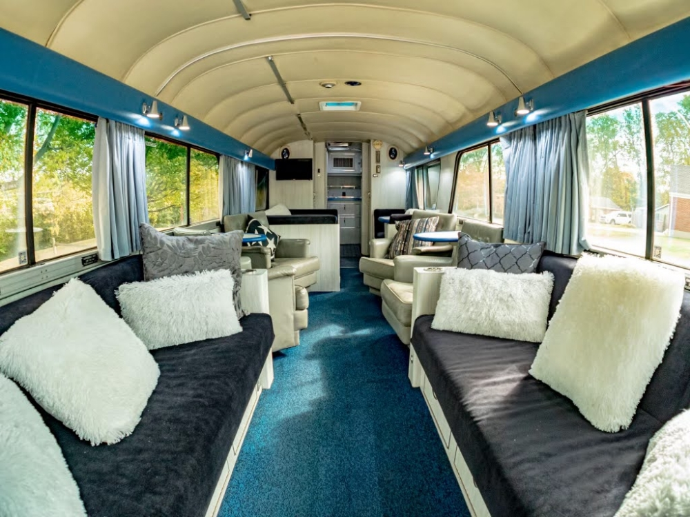 Spacious living area inside a 1976 MCI 8 bus conversion for sale, featuring plush seating and large windows, perfect for executive travel or luxury conversions.