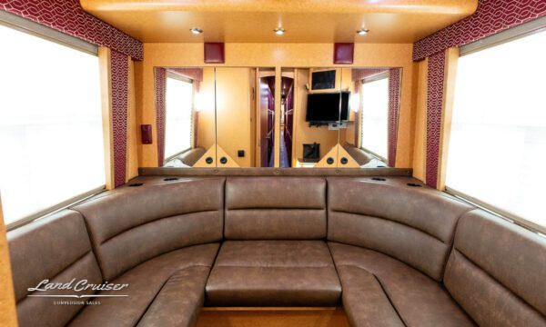 Curved leather sofa in motorhome rear lounge with cupholders and wood panel accents