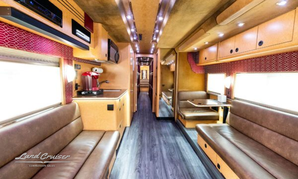 Motorhome interior hallway leading to rear lounge with overhead storage and soft lighting