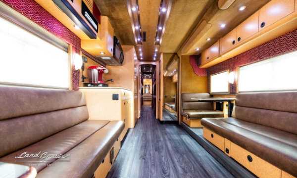 Spacious motorhome interior with dual seating lounges, LED ceiling lights, and wood flooring