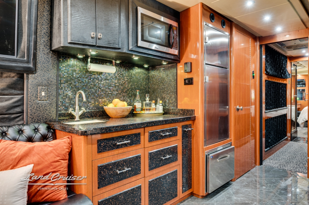 Galley area with storage and granite counters in Prevost bus conversion.