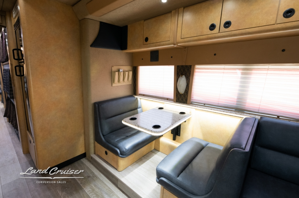 Another dining area view showcasing the comfortable seating and blinds inside a prevost entertainer bus.