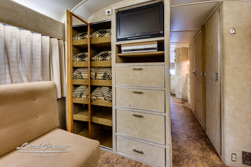 View of lots of storage and tv inside a bus conversion.