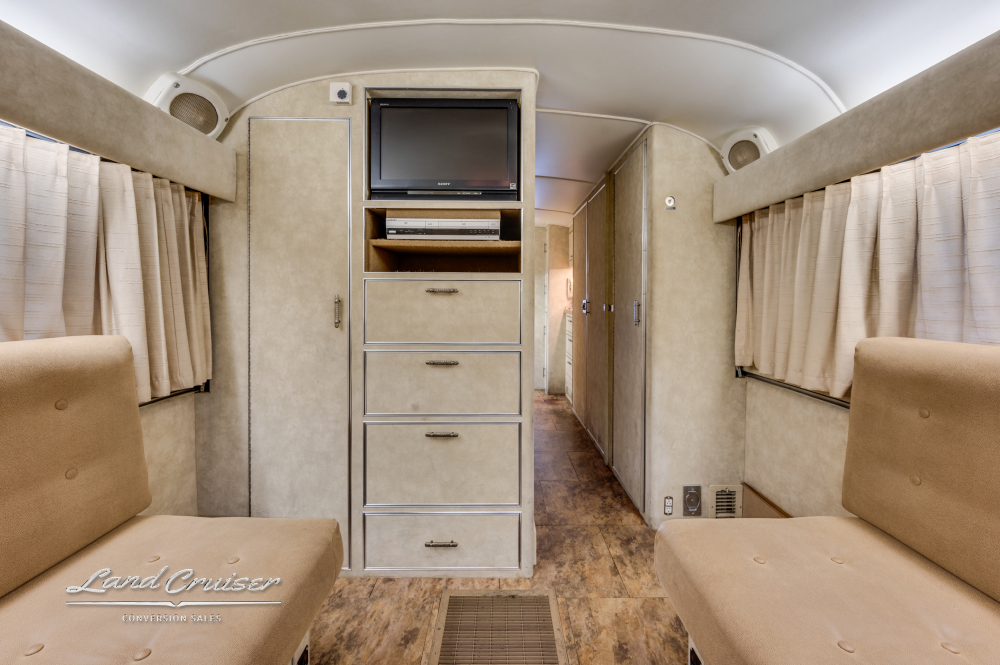 View of the lounge area with a tv, curtains, and seating inside a custom coach.