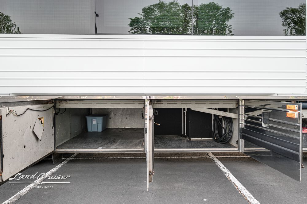 Open underbay compartment beneath extended slide on Prevost XLII with carpeted cargo space