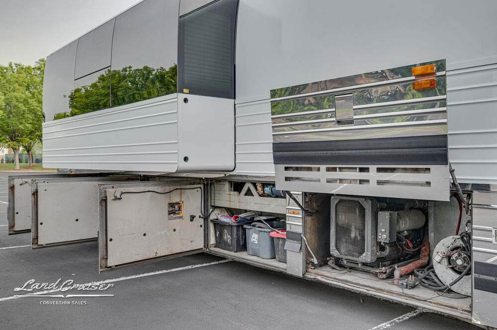 Open underbay compartment beneath extended slide on Prevost XLII with carpeted cargo space