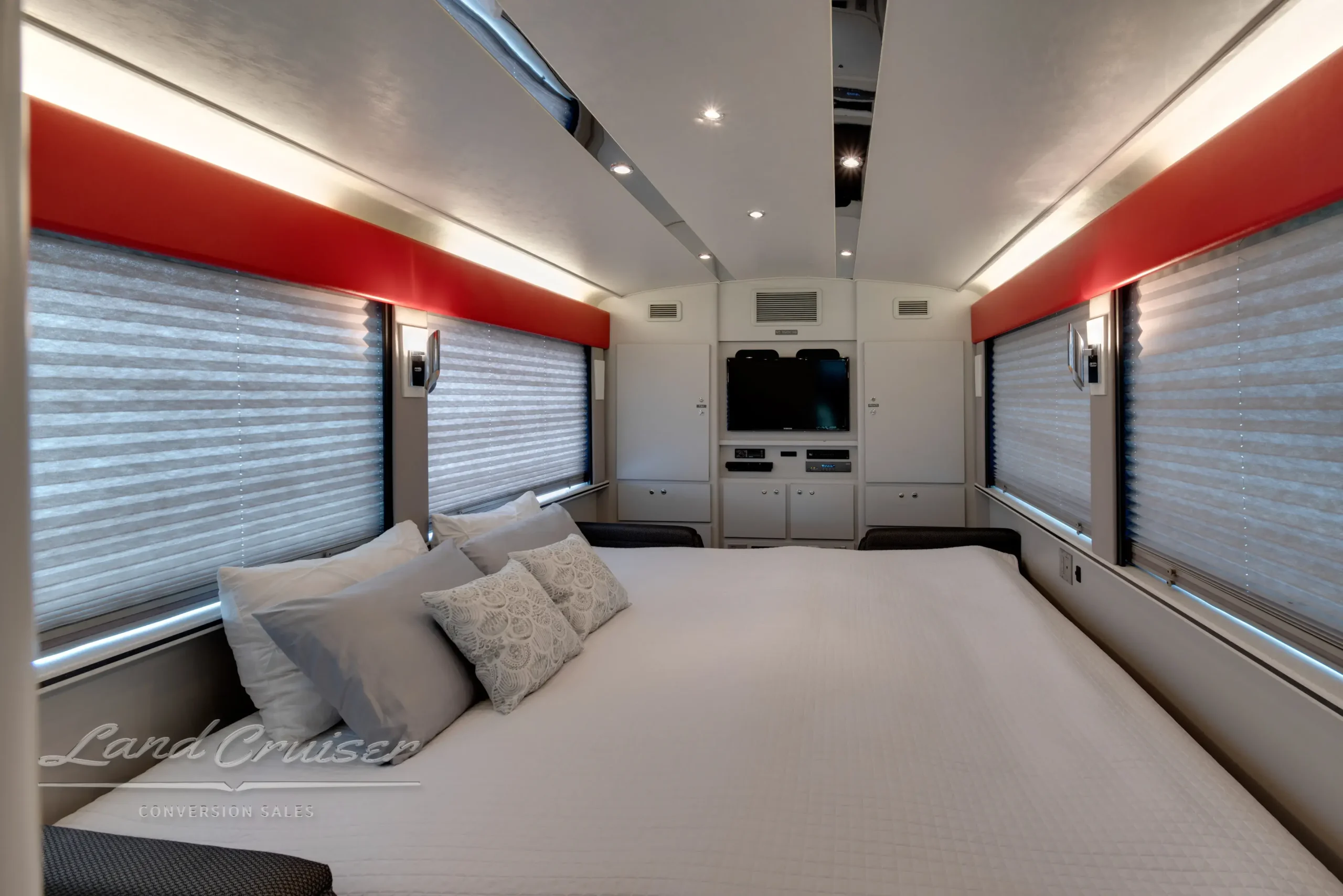 Luxury MCI motorhome bedroom with large bed, neutral bedding, and panoramic windows