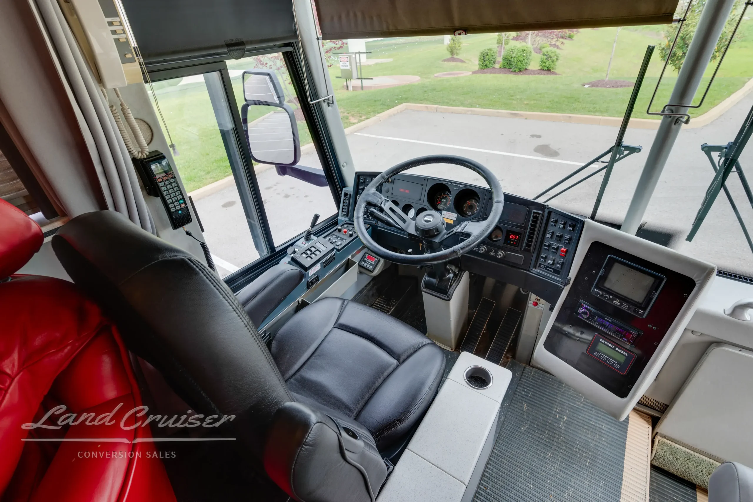View of MCI bus cockpit with black leather driver’s seat and wide entry windshield