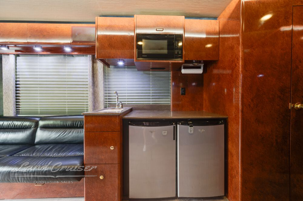 Galley sink and solid surface countertop in Prevost XLII coach with cherry wood cabinets and accent lighting