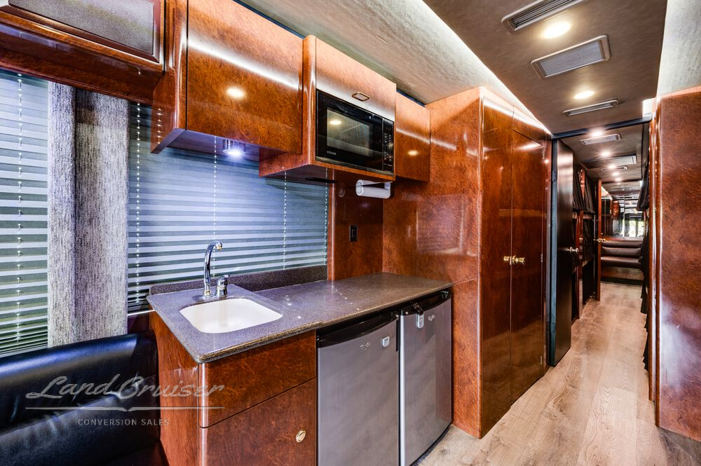Galley sink and solid surface countertop in Prevost XLII coach with cherry wood cabinets and accent lighting