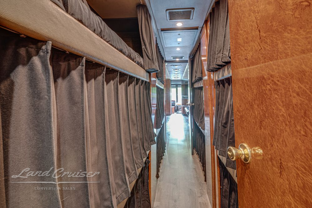 Interior view of bunk area in Shogun coach showing fabric curtains and clean bedding