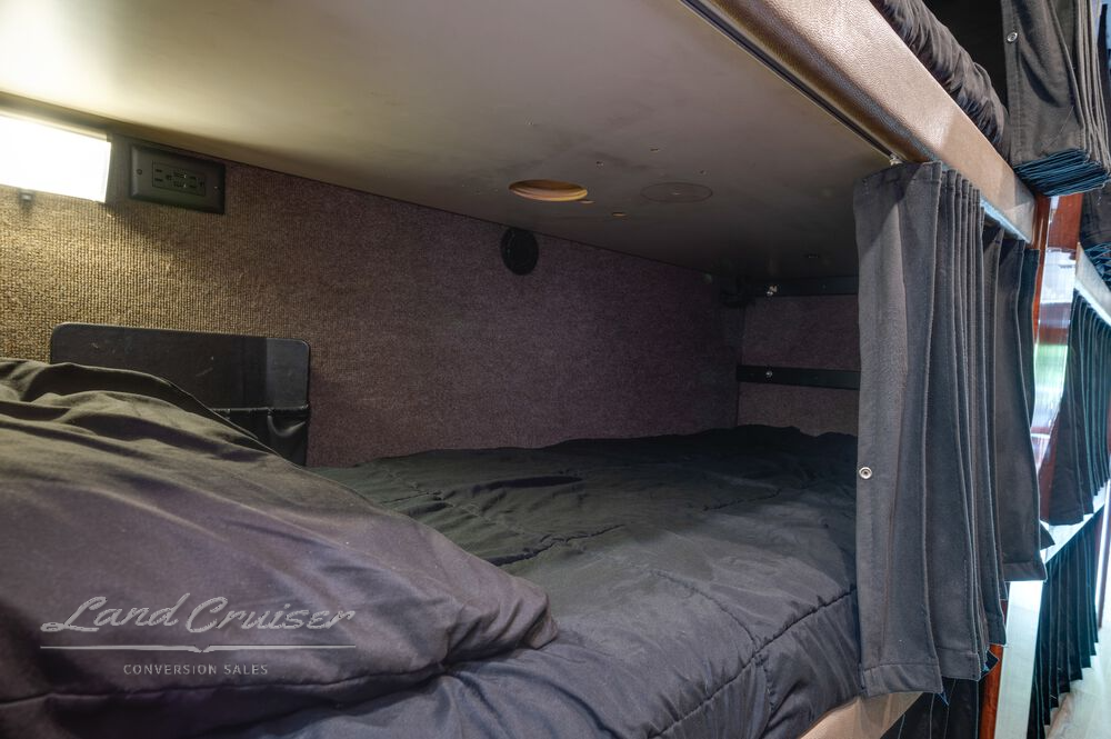 Single bunk bed in Prevost XLII coach featuring mattress, pillow, and personal lighting