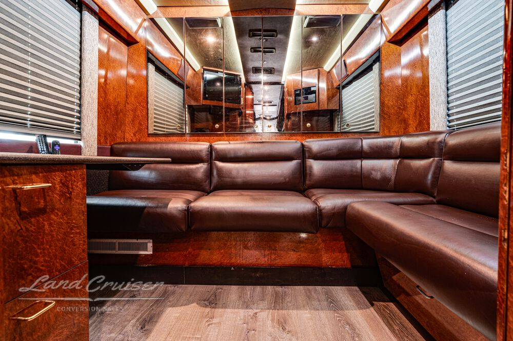 Rear lounge in Prevost Shogun coach with L-shaped leather sofa, hardwood floors, and LED ceiling lighting