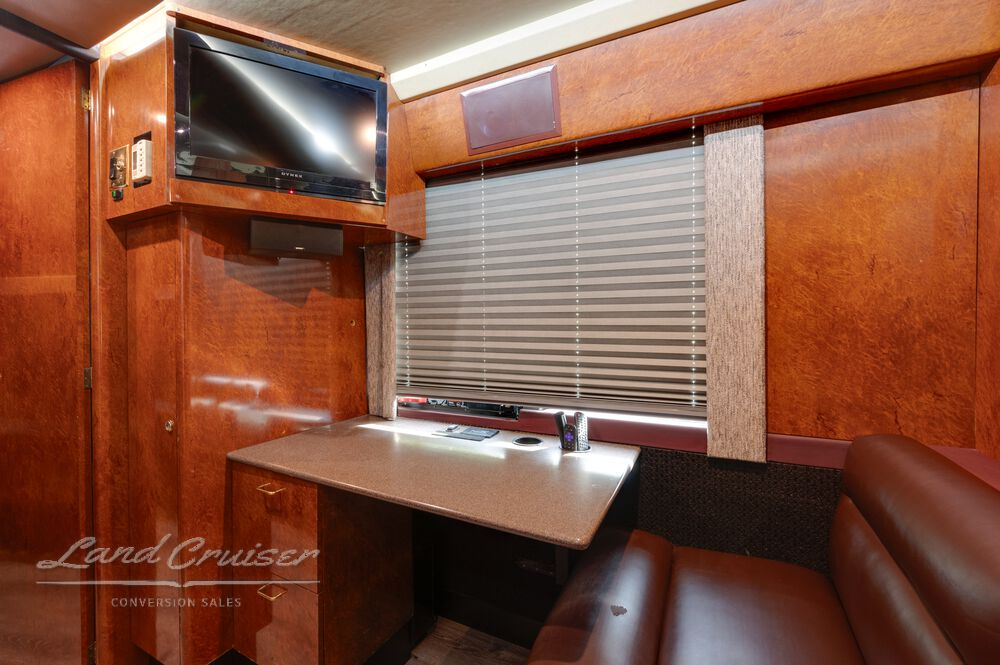 Workstation area in rear lounge of Shogun coach with flat screen TV, Corian counter, and leather bench seat