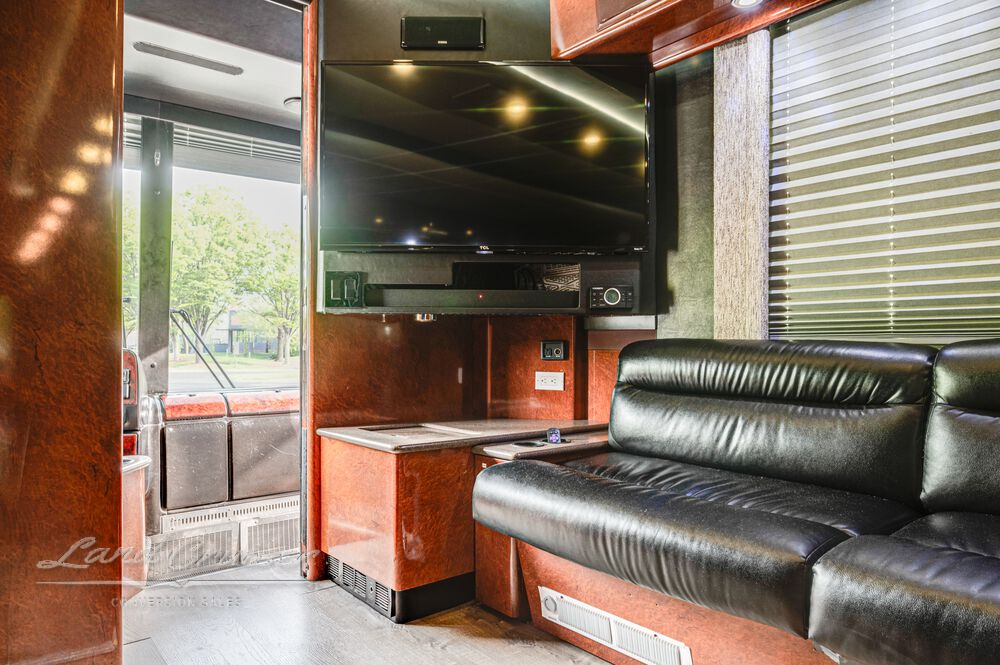 Passenger side view of front lounge in Prevost coach with sofa, galley entry, and side door access