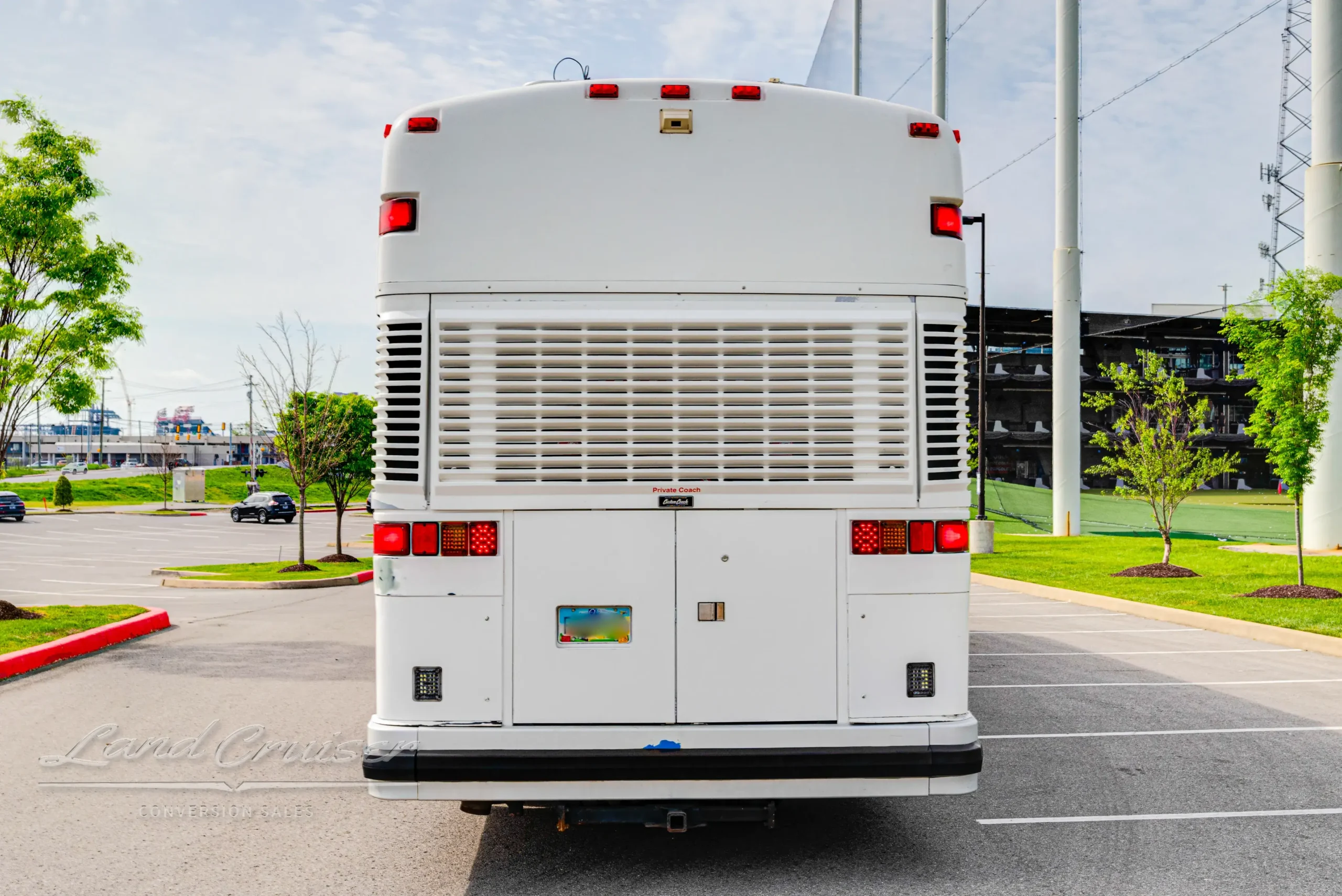 Rear view of MCI executive coach showing ventilation grille, tail lights, and road-ready stance
