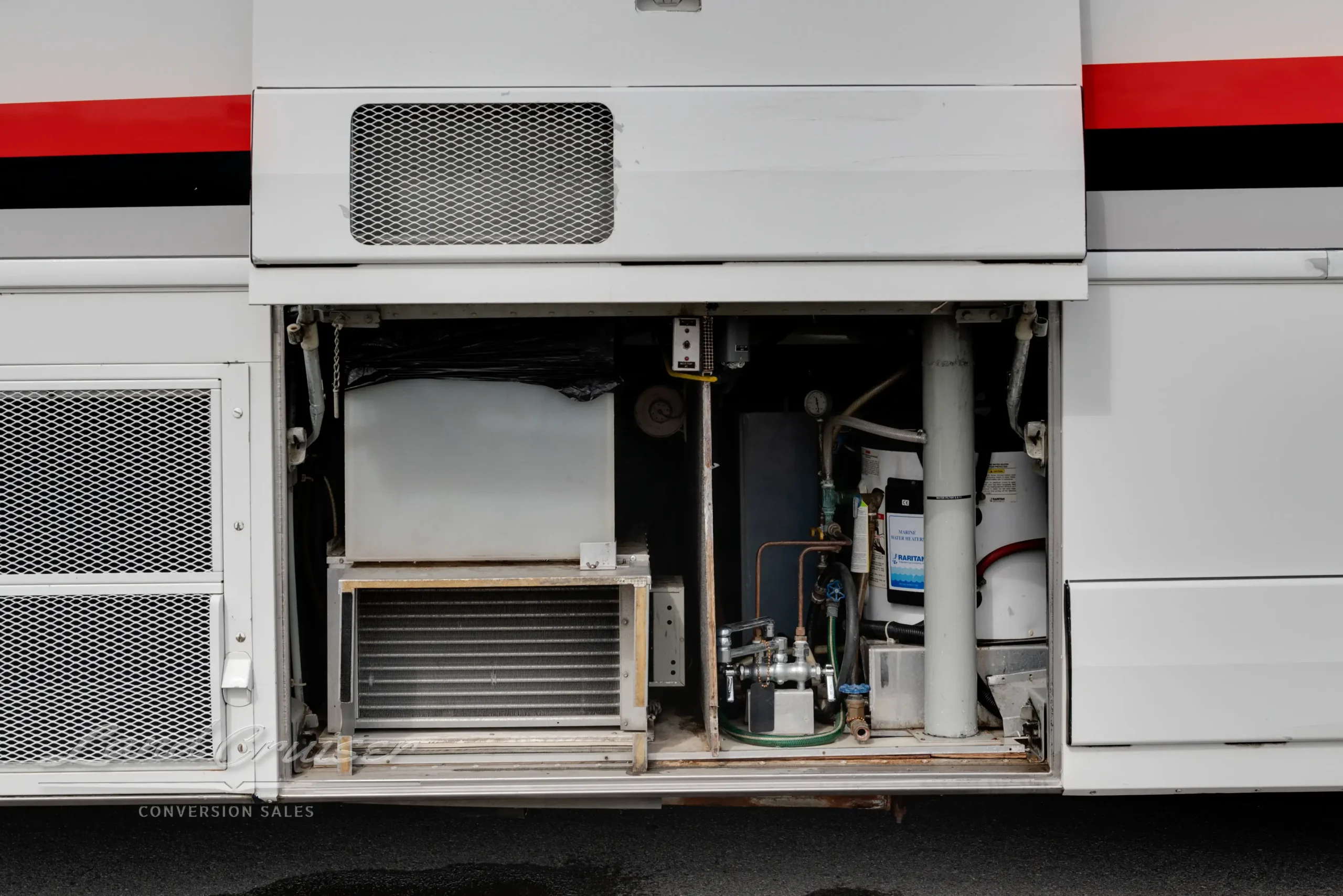 Side utility compartment of MCI bus featuring tanks, filtration system, and plumbing access