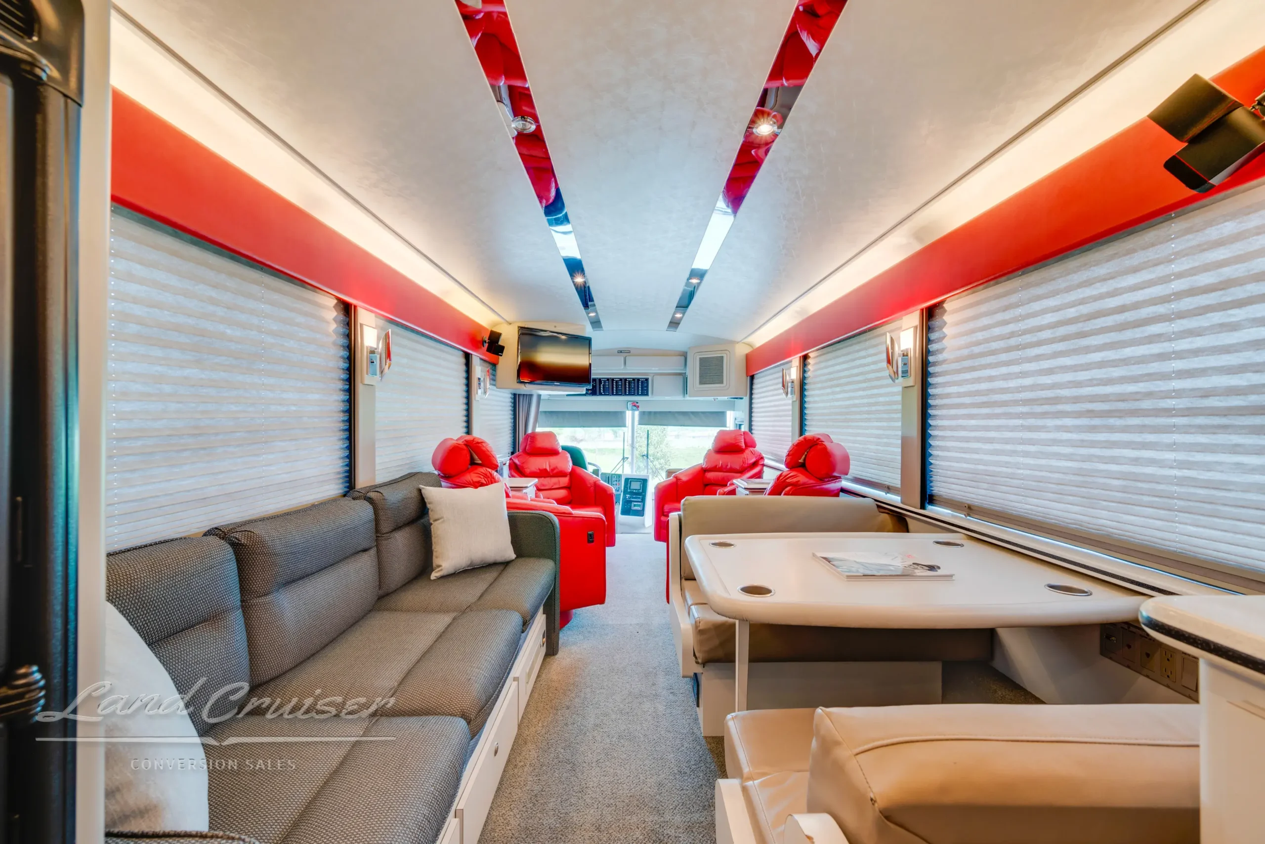Interior of MCI Executive Day Coach with swivel chairs, booth dinette, sleeper sofa, and Berber carpet