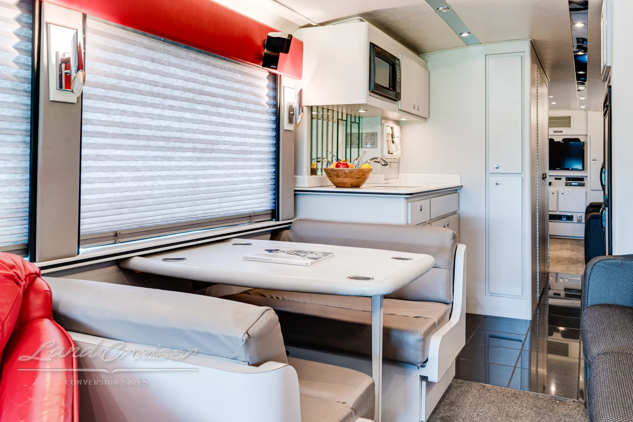 Booth-style dinette and galley area in MCI Executive Day Coach with solid surface countertops and accent lighting