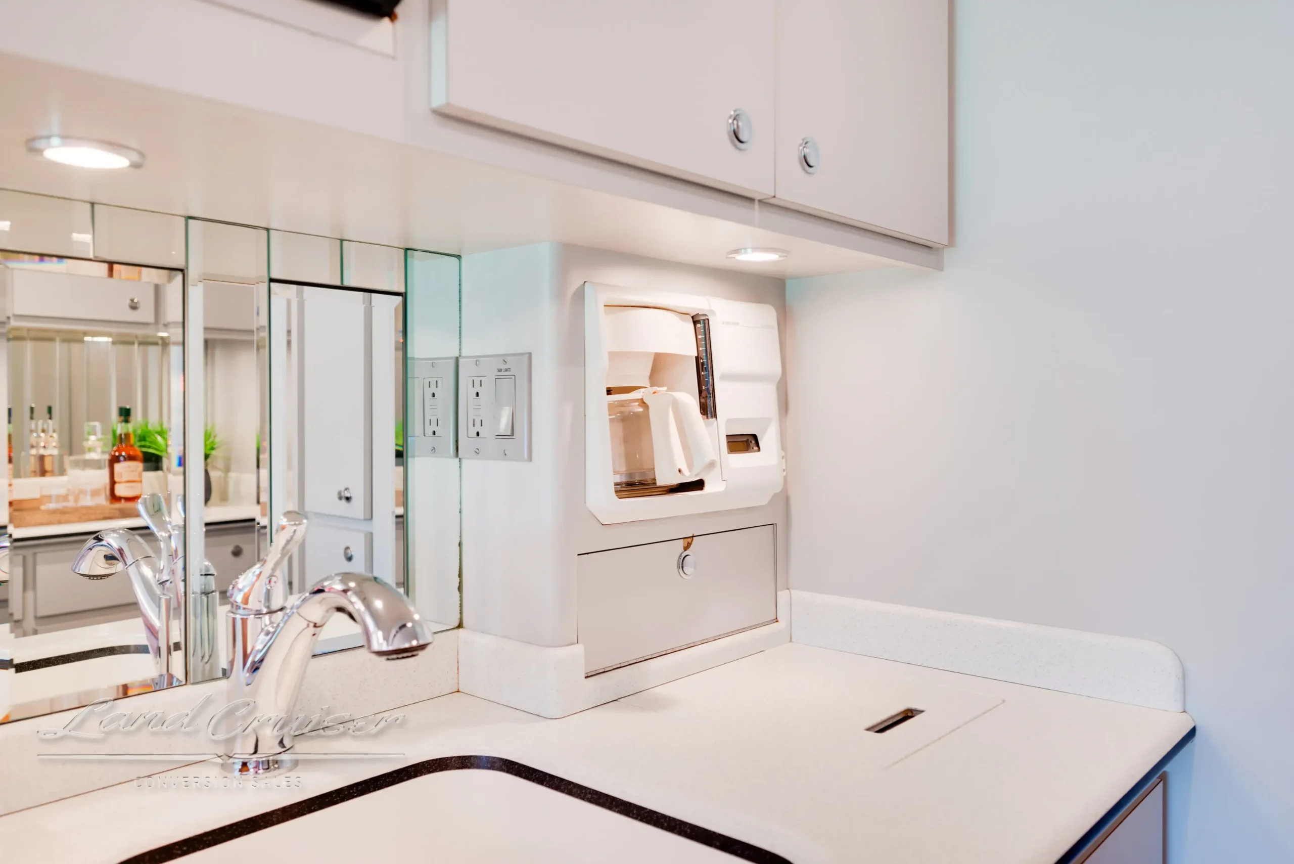 Built-in coffee bar and sink area in MCI motorhome with mirrored wall and undercounter storage
