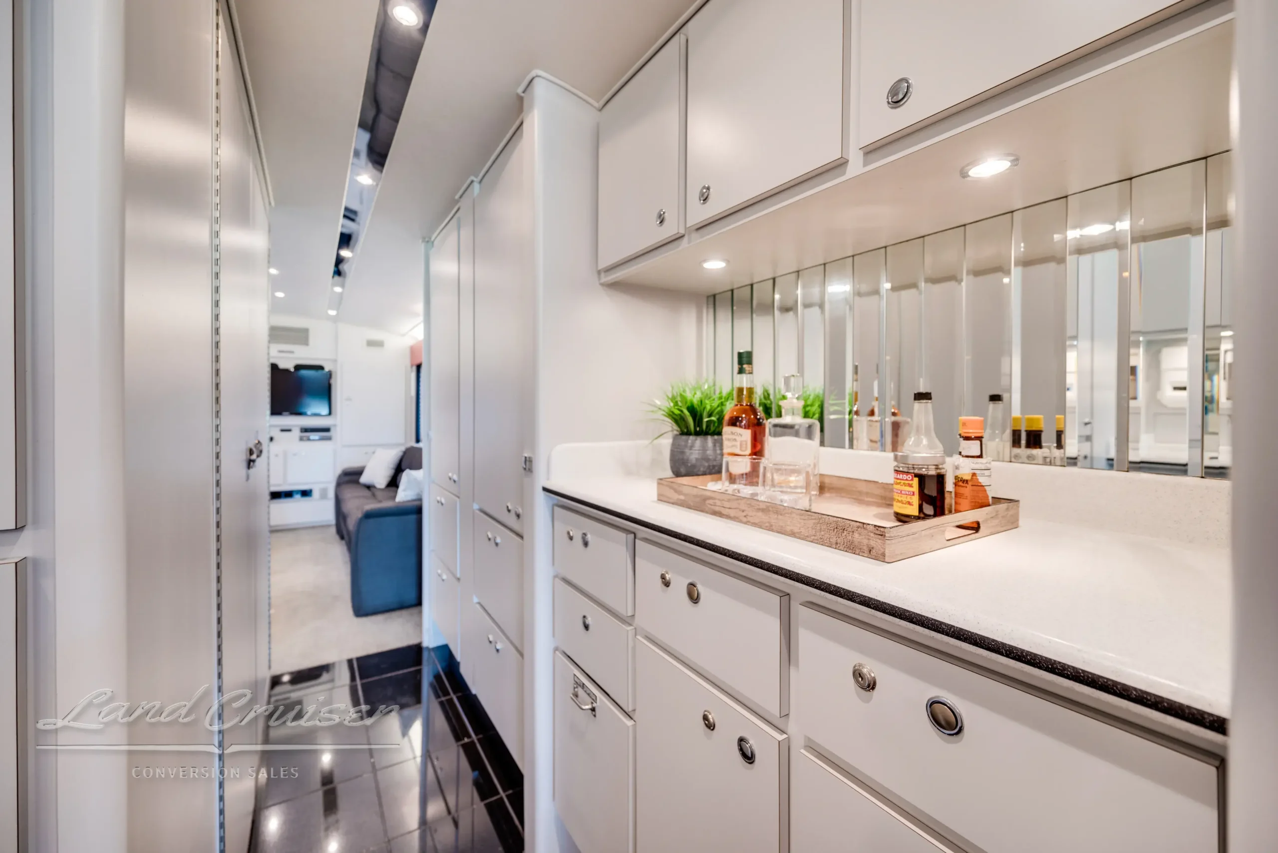 Kitchen in MCI Executive Coach lined with white cabinetry, mirrored backsplash, and modern decor accents
